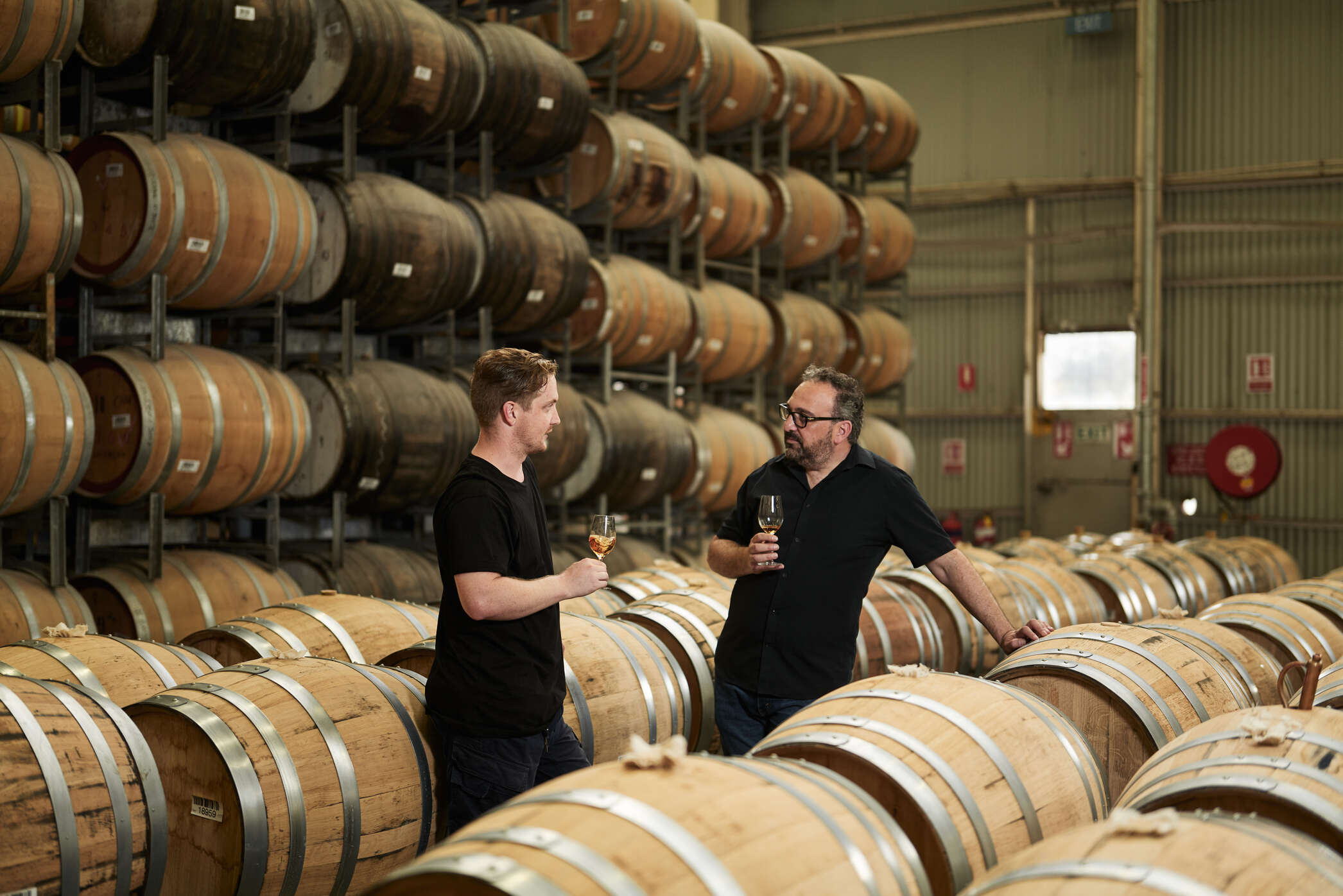 Two people tasting whisky directly from the barrel at Starward disitllery in Port Melbourne