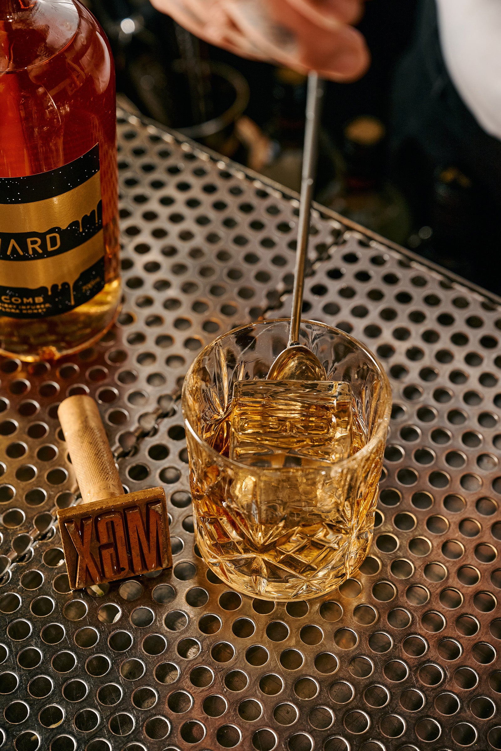 A cocktail with Honeycomb whisky being stirred on a sliver bar at Bar Marqaux