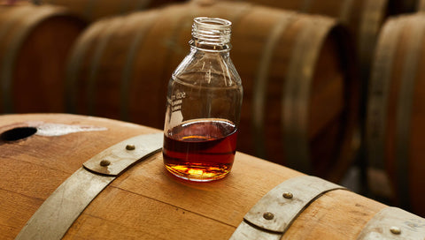 Whisky mixing bottle sitting ontop a wine barrel from Starward Whisky