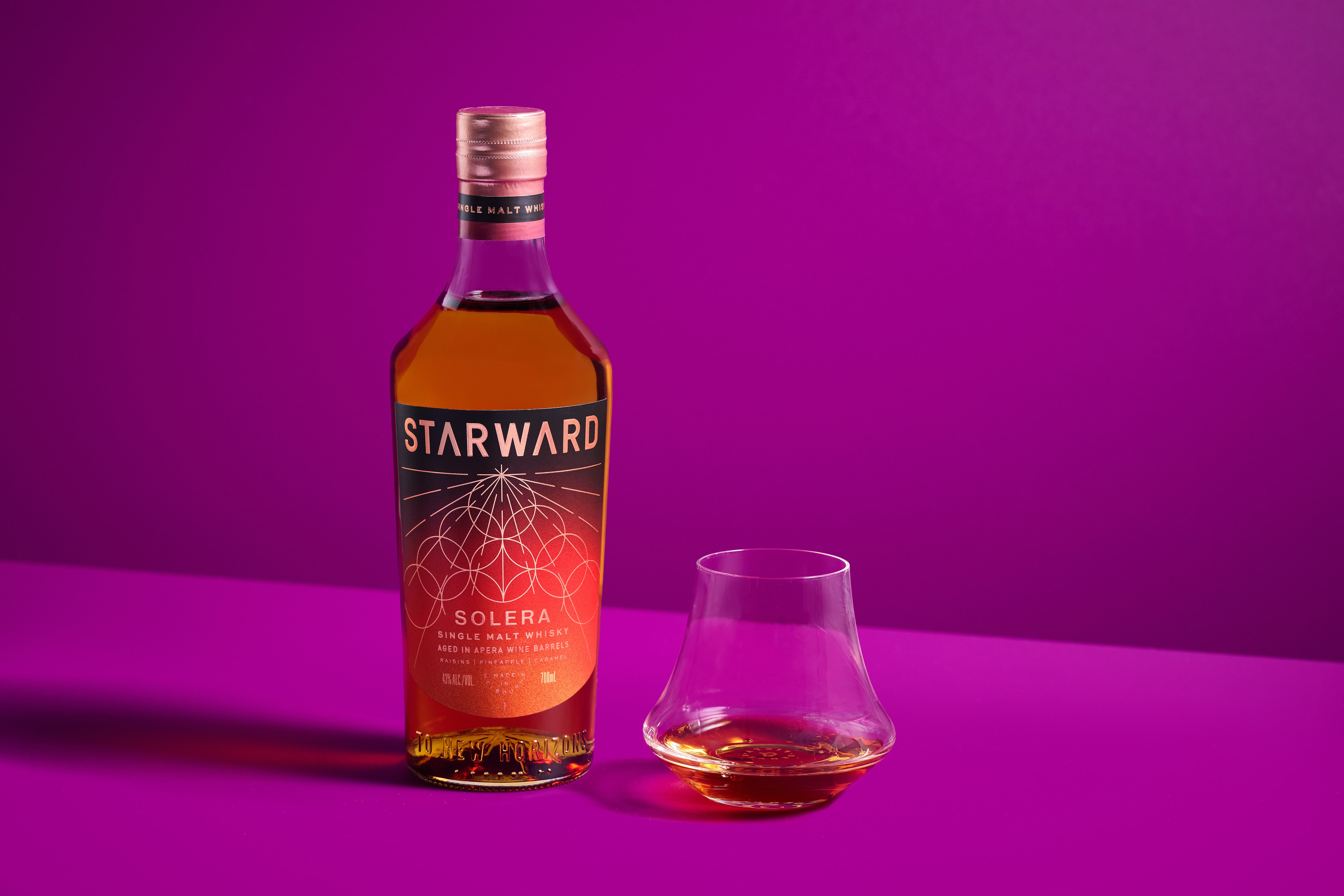 Starward Solera whisky from australia with a glass of neat whisky on bright background