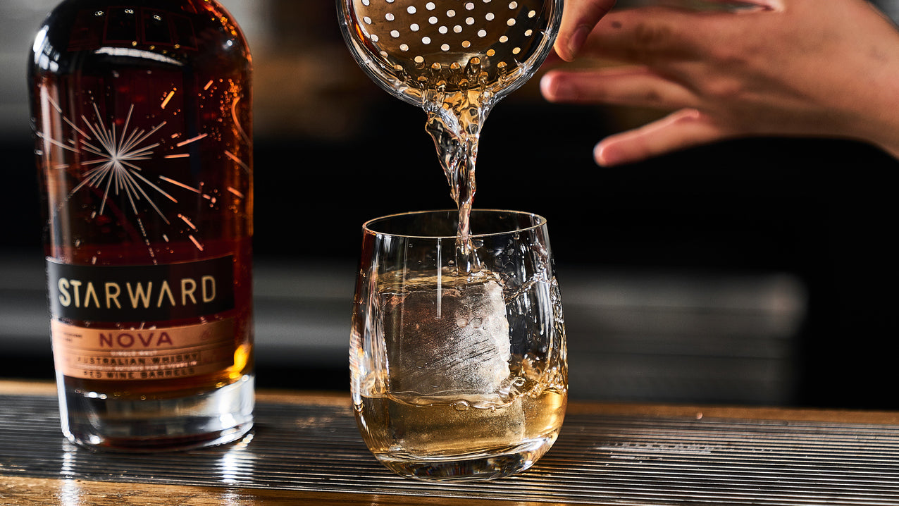 Whisky Cocktail making at a bar with a bottle Starward Whisky and a bar tenders hands