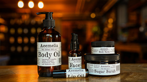 Aeemelia Skincare products, face oil, body oil, body balm and sugar scrub laid out on a table