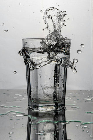 A close-up of a glass of water splashing on a table.