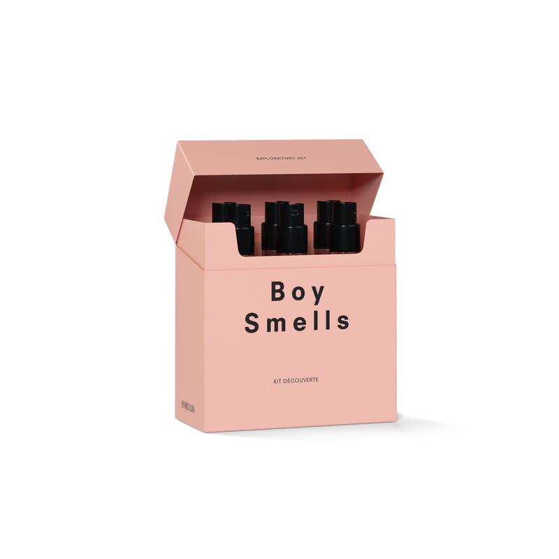 3/4 pack shot of exploratory set in pink cigarette style box with logo and black text open with nozzles of 1.5 oz perfume vials peaking out the top