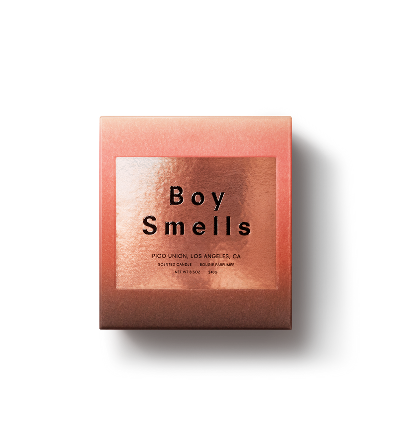 Product shot of exterior Slow Burn peach box with a metallic square containing the boy smells logo and black text against a neutral background.