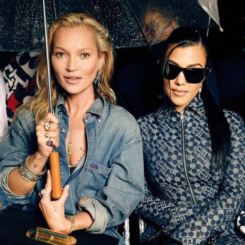 Two women looking at the camera, one holds an umbrella