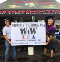 Witchdoctors holds sign with Wheels4Warriors