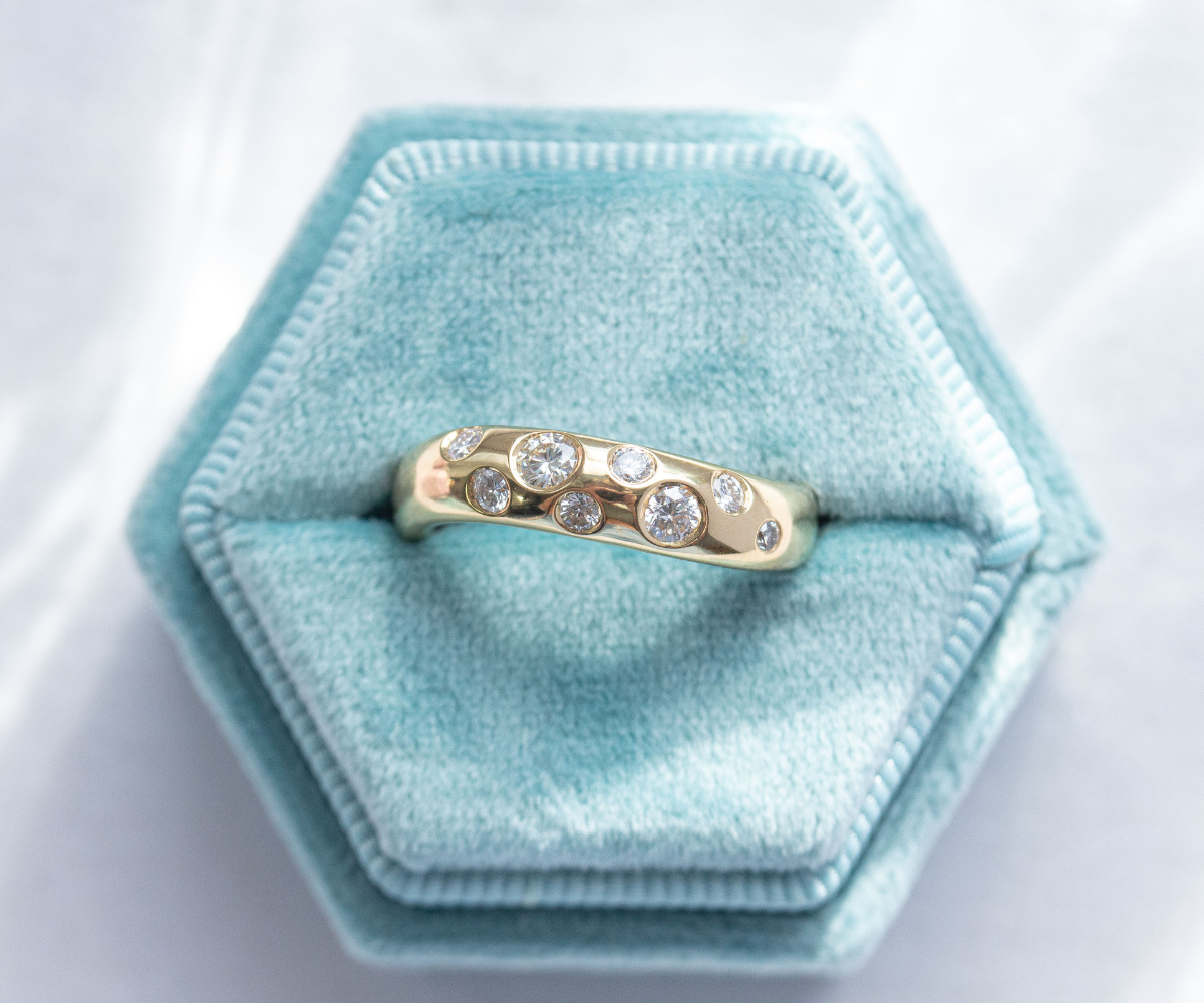 solid 18k yellow gold waved band with flush set diamonds