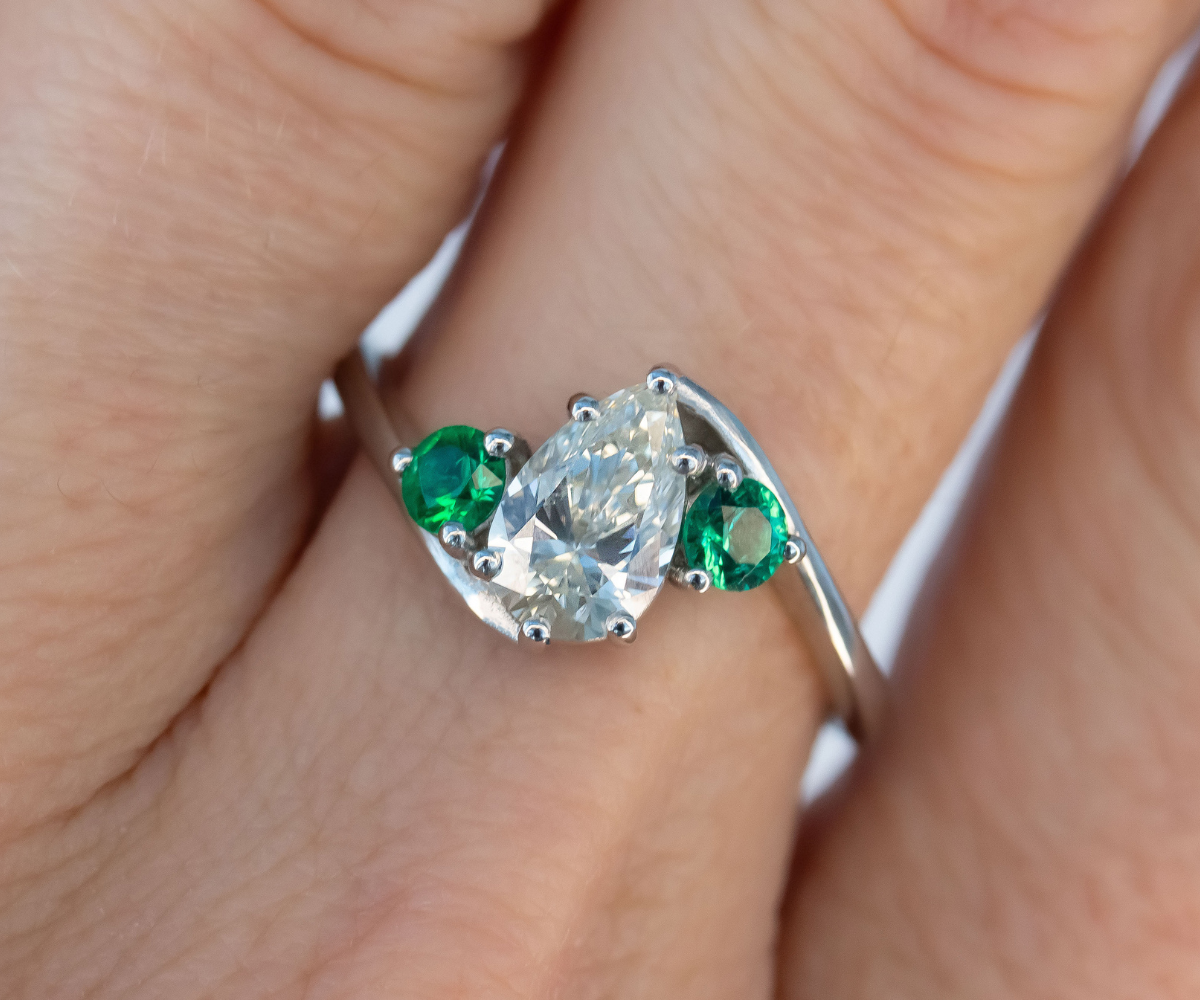 Pear Diamond and green round Emerald 3 stone twist engagement ring in platinum