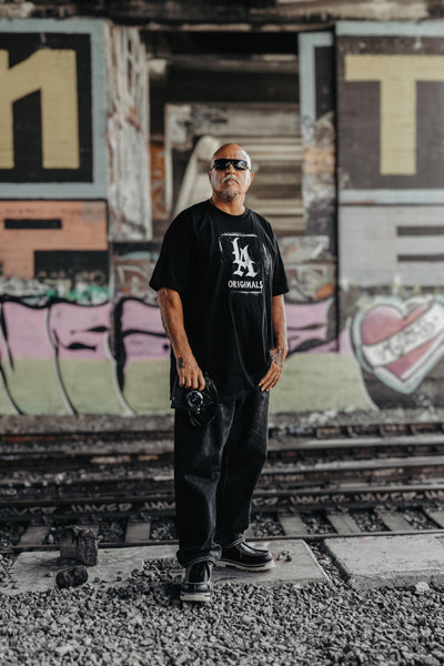 Estevan Oriol poses in front of train tracks with his camera in hand.