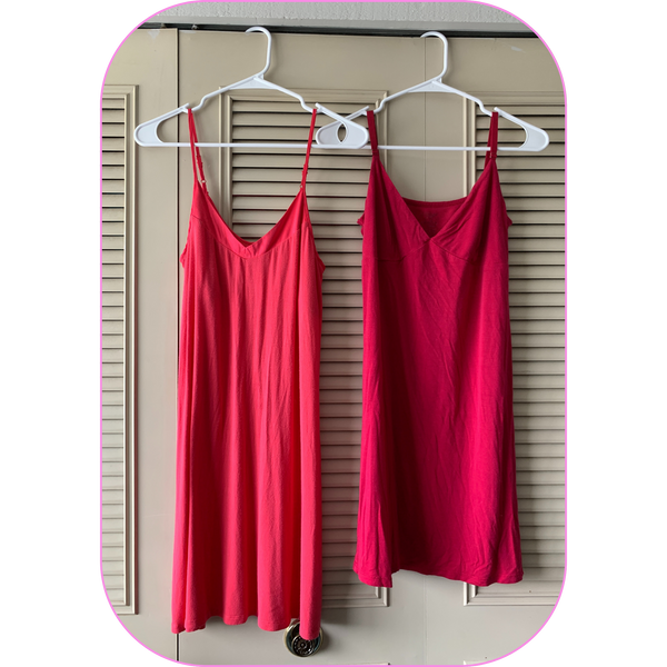 a pair of slip dresses hanging on the door of a closet