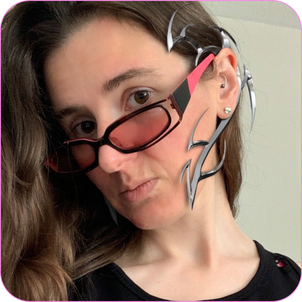 headshot photo of a woman wearing futuristic pink and black sunglasses with a silver digital ear cuff