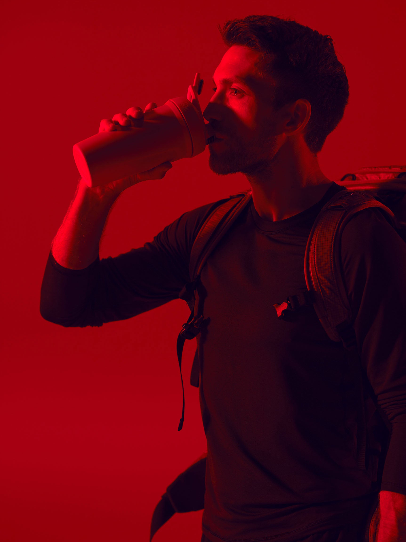 Man drinking protein shake from red shaker bottle