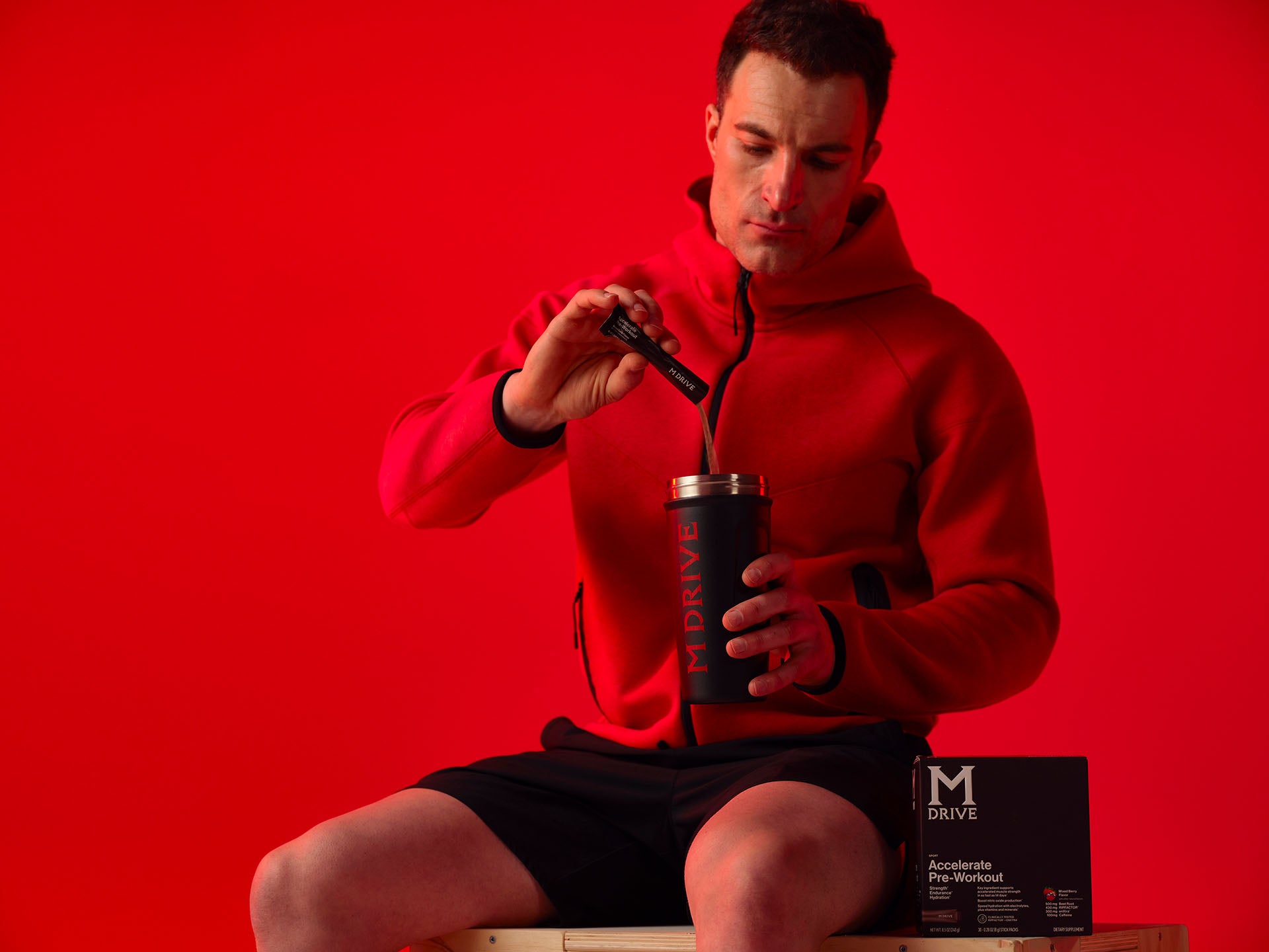 Man pouring M Drive Accelerate pre-workout into a shaker.