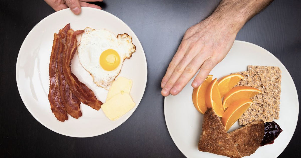 Plate of eggs, bacon, cheese vs grains and fruit.