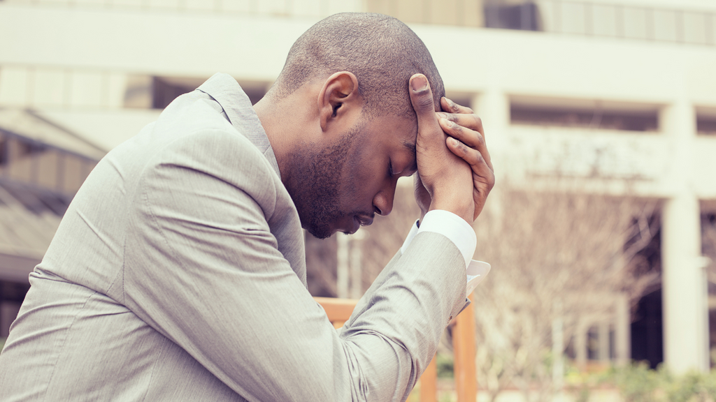 Man with head in hands looking stressed and tired.