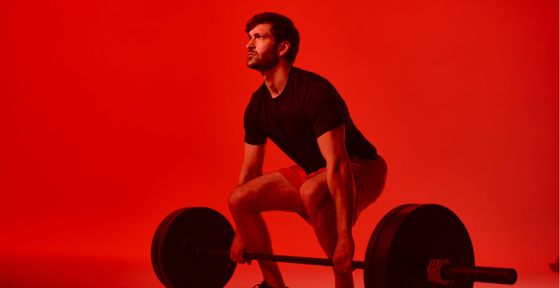 Man deadlifting a barbell on a red background