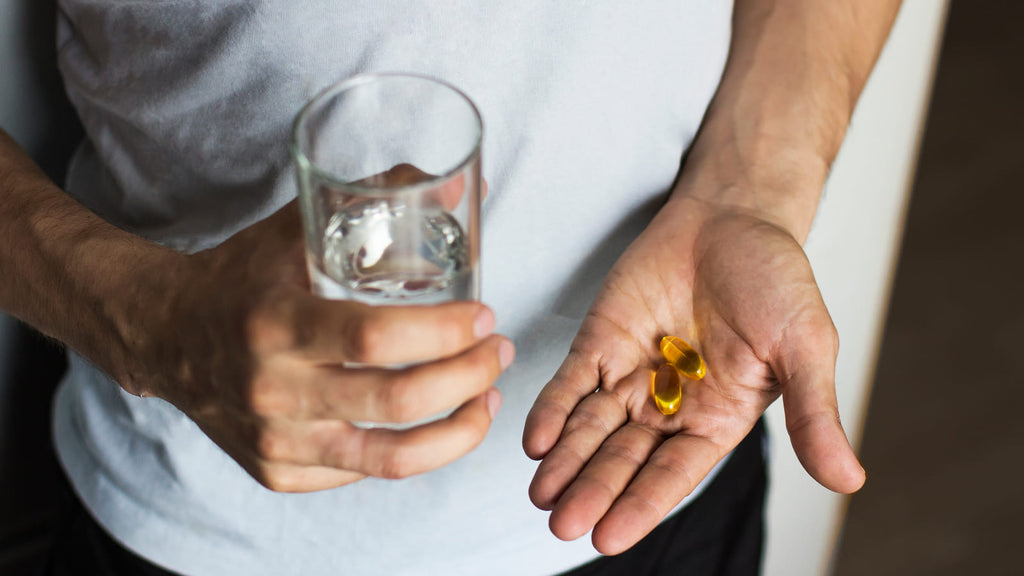 Man taking supplement capsules. Certain supplements can help boost libido.