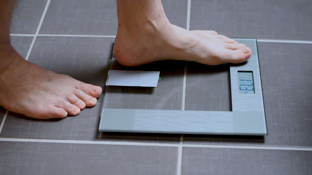 Man stepping on scale | Testosterone to Help You Lose Weight?