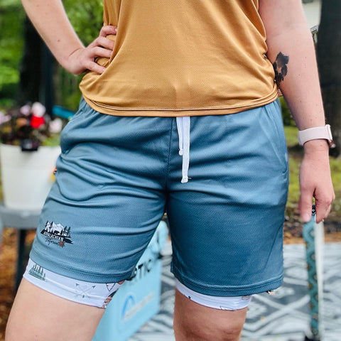 Person wearing 2 in 1 long hiking shorts and posing outside with hand on hip.
