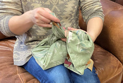 Image of hands wrapping a book in a scarf wrap.