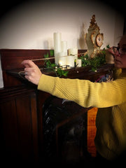 Shop Elf (staff member) measuring string over mantlepiece to hang the pouches