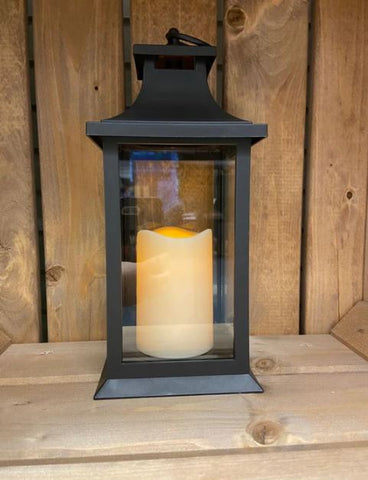 Image showing a black plastic lantern with lit LED candle inside clear plexi panels.