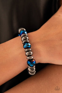 Power Pose - Blue May 2022 Life of the Party Bracelets an oversized assortment of textured gunmetal rings, smooth gunmetal beads, and metallic blue crystal-like beads are threaded along stretchy bands around the wrist for a glitzy finish.  Sold as one individual bracelet.  Get The Complete Look! Necklace: 
