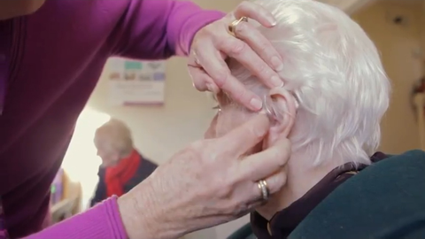 a clinic volunteer fitting a moulded hearing aid