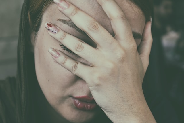 Woman suffering from fatigue due to psychological effects of chronic pain with hand over face