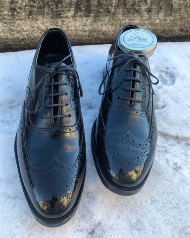 Johnston Murphy Crown Aristocraft Black Wingtips mirror shined and reflected in the snow with Pure Polish Black Paste on the top