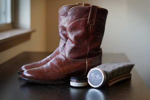 Restored leather men’s cowboy Justin boots fixed scratches next to a horsehair brush and jar and tin of Pure Polish