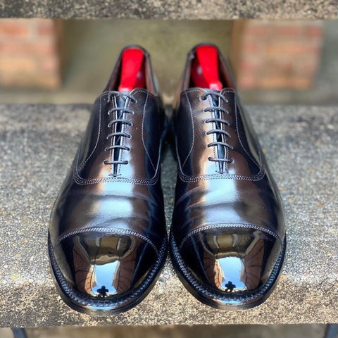 A pair of black cap toe calfskin oxfords mirror shined with Pure Polish High Shine