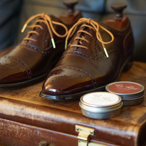 Vintage pair of Church’s Custom Grade Semi Brogue Oxfords polished with Pure Polish creams and waxes on a leather briefcase and black couch.