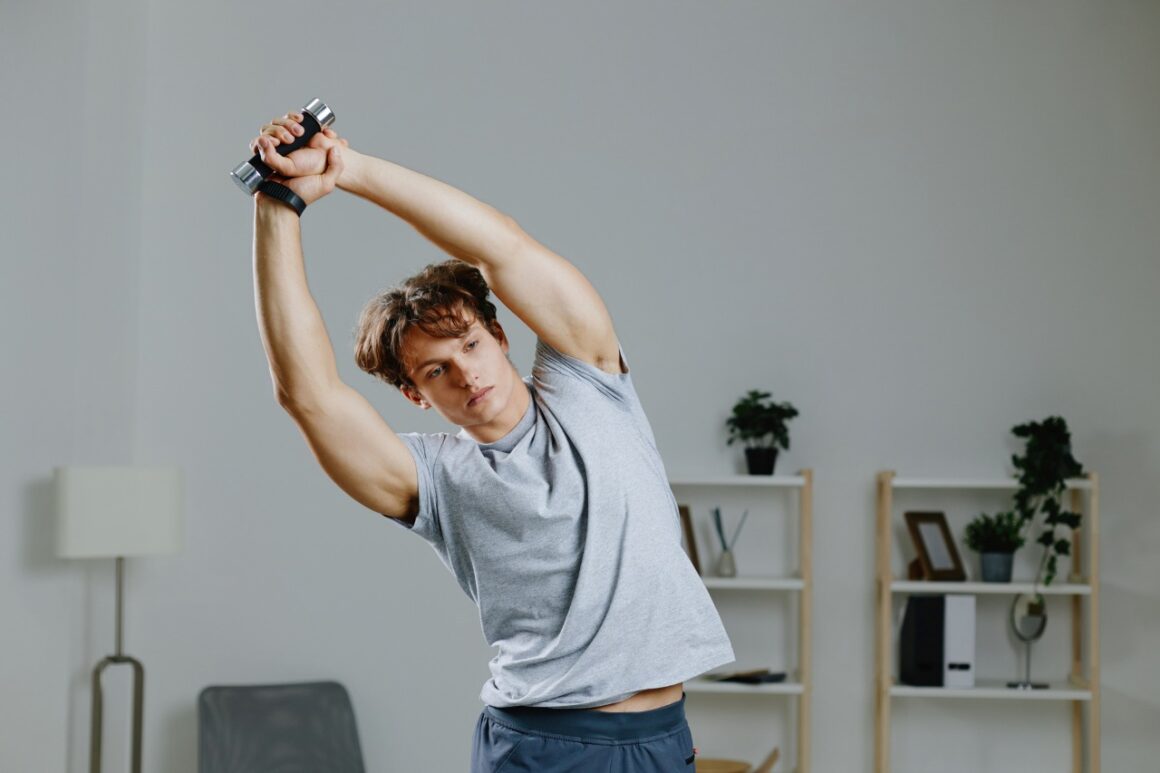 man stretching while holding a small dumbbell