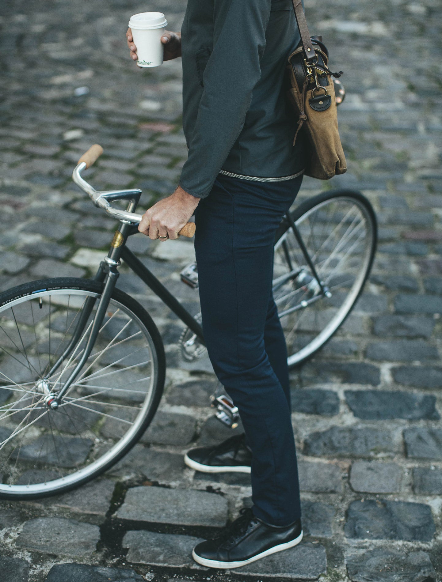 A gentleman stands with a bike. We know he's a gentleman because he's carrying a coffee — and wearing CIVIC.