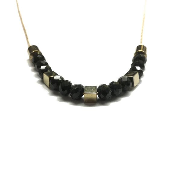 Gold brass tube bead with black faceted glass beads and gold square hematite bead spacers on a thread necklace