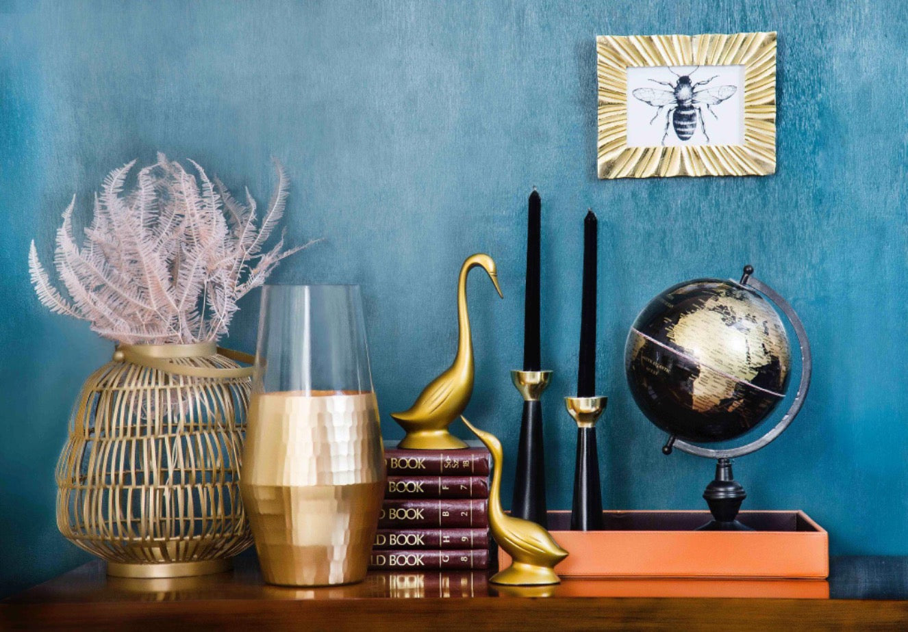 vintage home decor table with vase, globe, brass, books.
