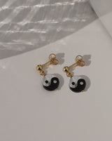 Yin Yang Earrings by KOZAKH. 3mm Ball stud earrings with 0.5 inch drop length, crafted in 14K Gold Filled, featuring a hand carved Mother of Pearl Yin Yang charm.
