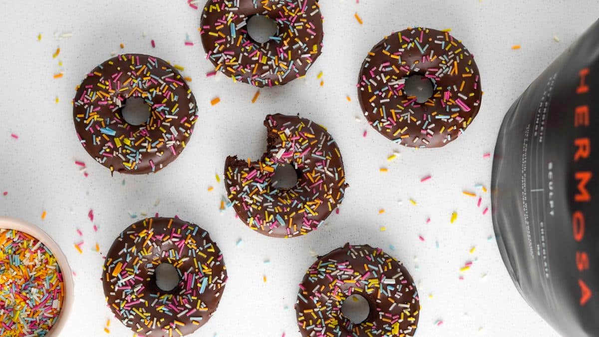 Six chocolate protein doughnuts on a white table.