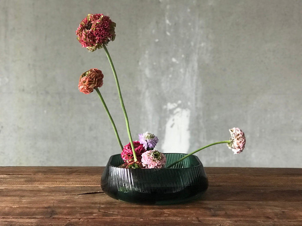 NUDE Glass Opti bowl with an Ikebana creation with ranoncules scabiosa Atlantis scoop