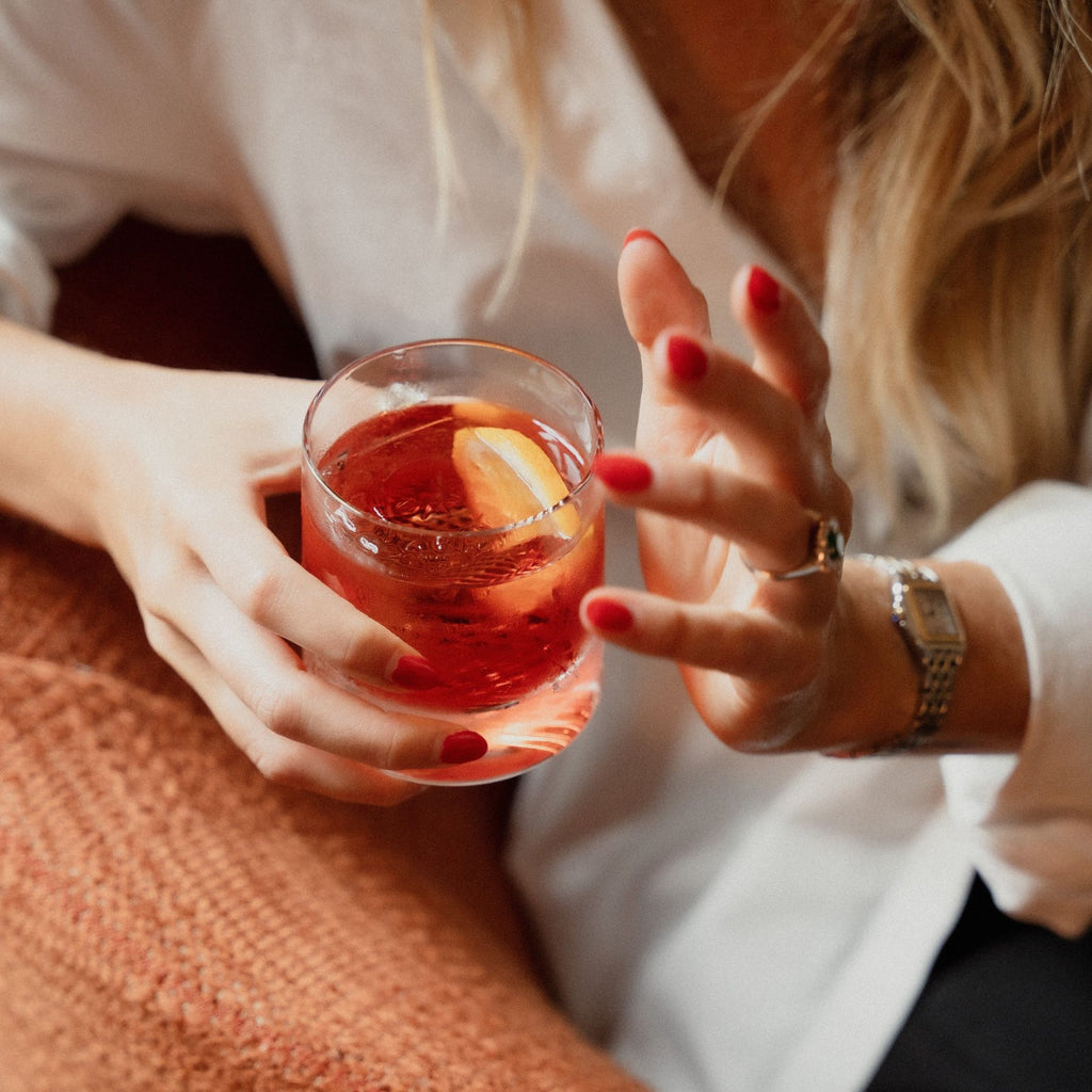 A negroni cocktail served in a NUDE Glass Alba glass enjoyed by a lady sitting on a sofa