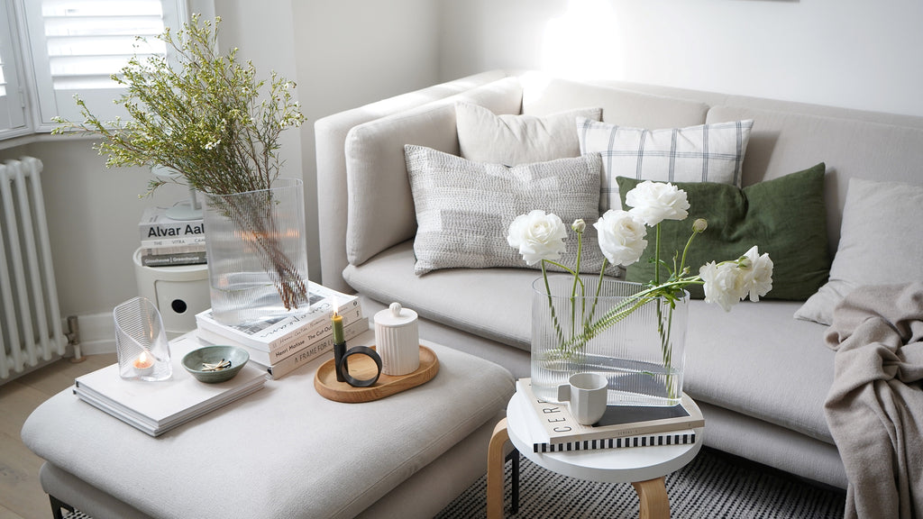 Lagom cozy scenery with neutral tones, a sofa with coffeetables, NUDE Mist vases in clear leadfree crystal and Mist Lights votives in clear leadfree crystal presented on the tables