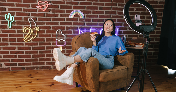 woman in chair eating pizza with brick wall in background making content: best influencer marketing platforms