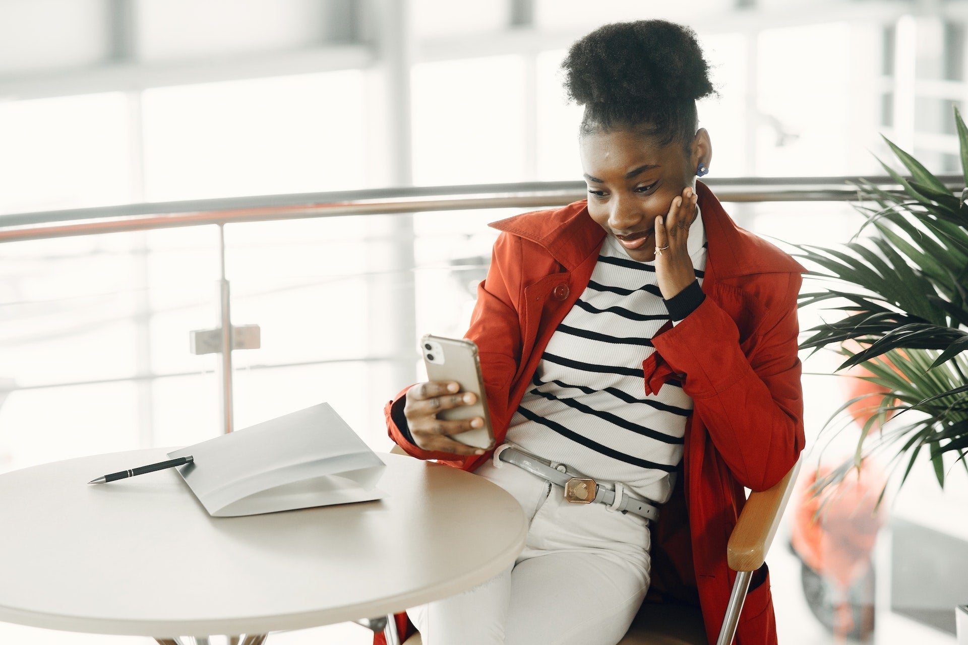 Image of a woman sitting on a chair at a table browsing the Twitter app on her phone