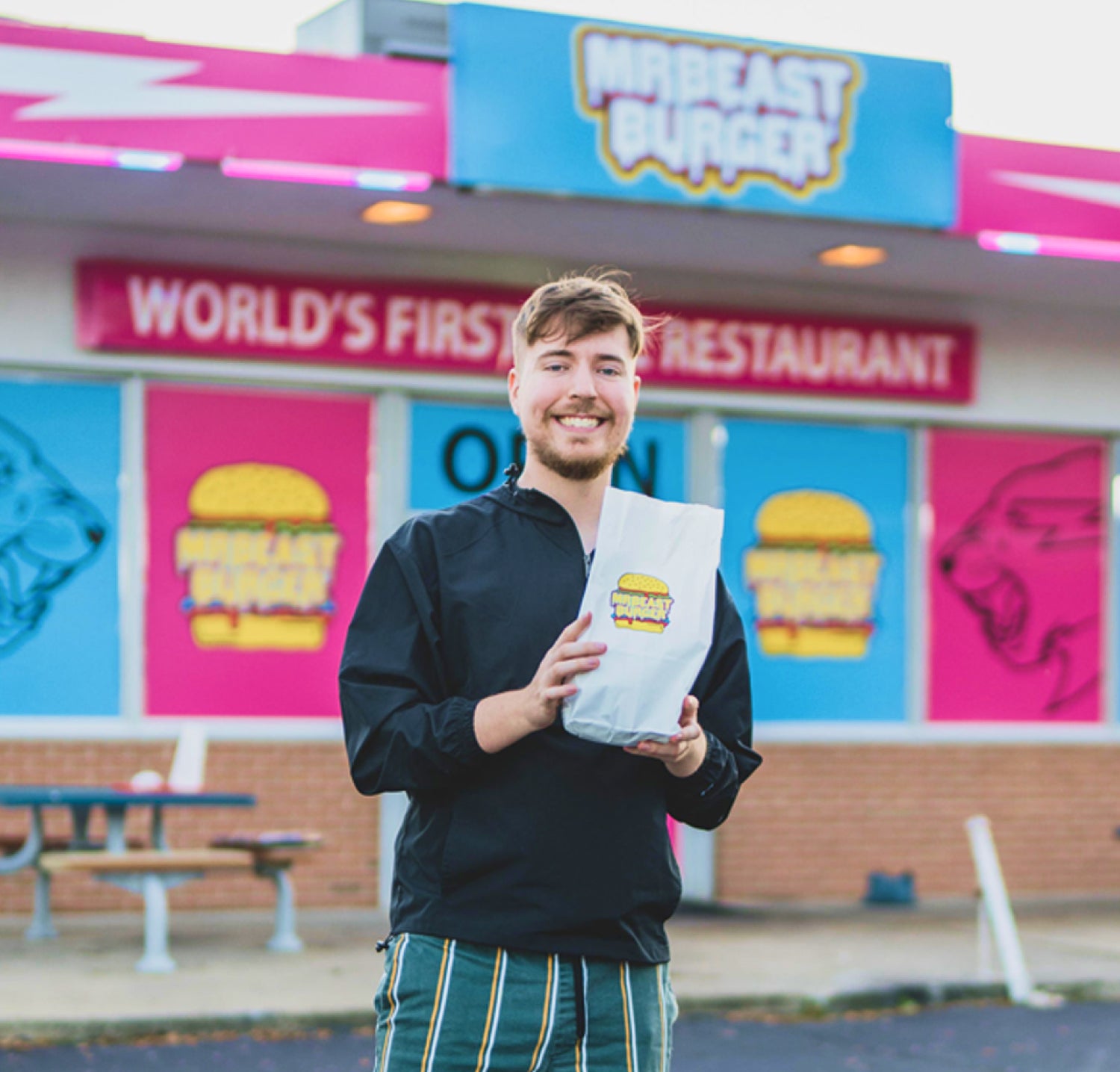 MrBeast holds a MrBeast Burger paper bag.