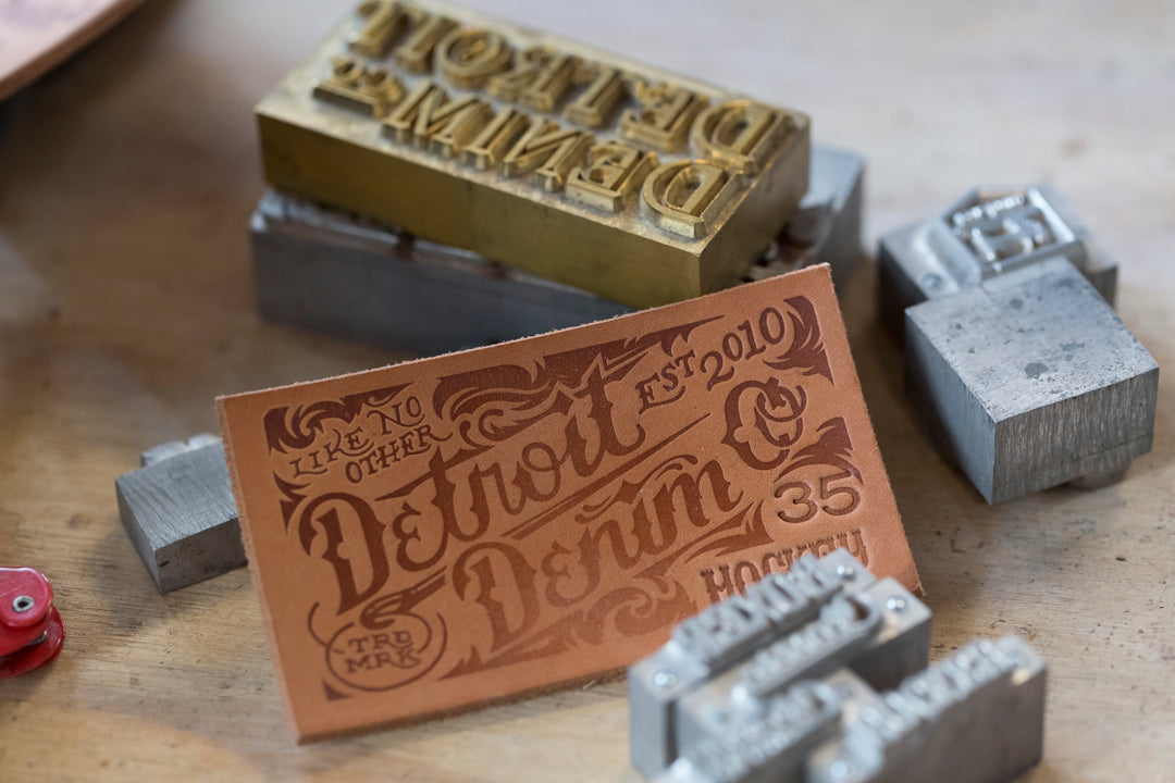 Detail of a Detroit Denim branded leather patch and metal stamps.