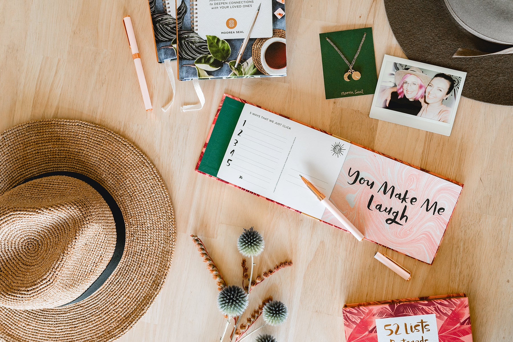 A shot from above a table with pens, a notebook, hats and jewellery