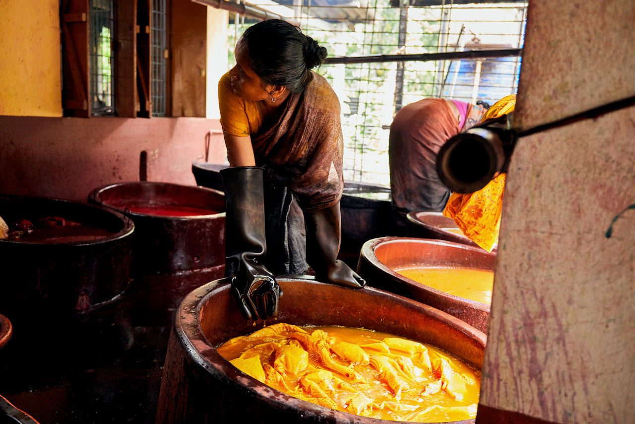 An artisan washes and dyes a saree fabric for Suta. 