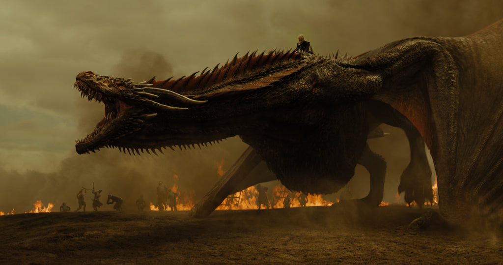 Image of Daenerys Targaryen riding a scaly dragon into a war scene with fires underneath them and people fighting